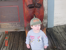 Hunter standing by a bear carving.